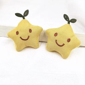 Detailed view of handmade plush yellow stars with embroidered smiles and green leaves