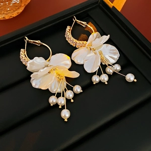Detail of elegant gold flower earrings with white petals and hanging pearl tassels