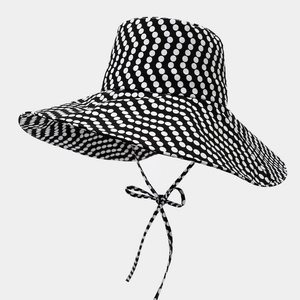 Dettaglio di un cappello da sole a tesa larga a pois con cinturino decorativo coordinato