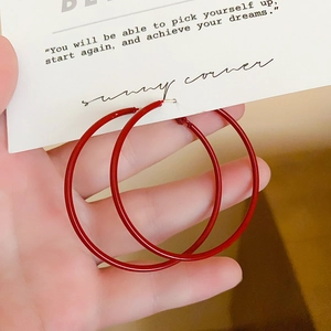 Close-up of vibrant red oversized metal hoop earrings on a white quote display card