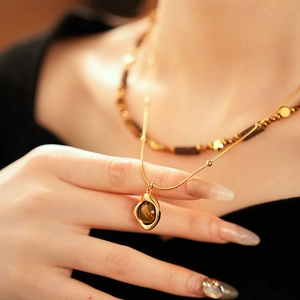 Dettaglio della collana a doppio strato in oro con pietra occhio di tigre e choker
