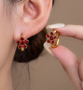 Detail of flower earrings with red zircons and 18k gold plating on a model
