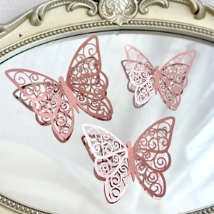 Detail of three rose gold hollow paper butterflies on a vintage gold rimmed mirror