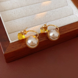 Detail of vintage gold pearl earrings with yellow gemstones on a beige velvet jewelry tray