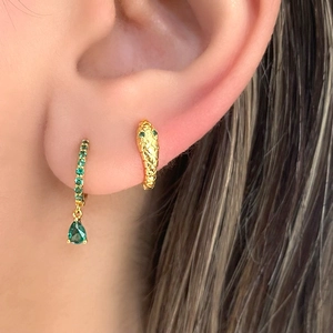 Close-up of gold drop earrings and snake stud featuring vibrant green zircon stones