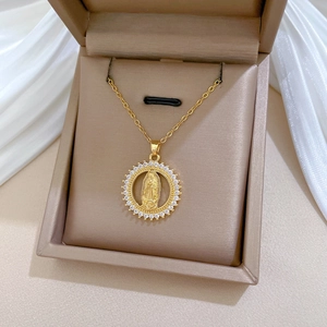 Macro detail of gold plated necklace featuring a saint portrait pendant with pavé zircons