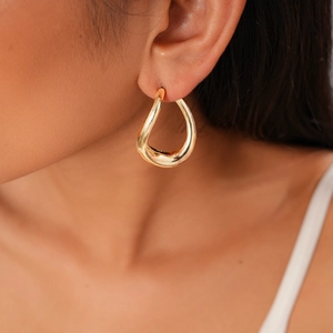 Close-up of elegant irregular golden hoop earring worn by model with minimalist style