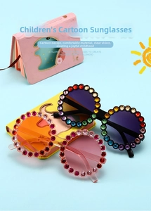 Detailed view of round frame kids sunglasses with colorful rhinestones on light blue background