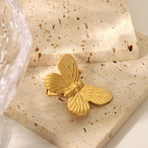 Detailansicht einer goldenen Schmetterlings-Haarspange mit Flügeltextur auf Stein