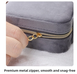 Close-up of smooth gold zipper detail on a grey velvet jewelry storage box
