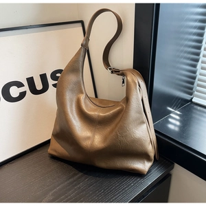 Detailed close-up of brown PU leather hobo bag on black wood surface with soft lighting