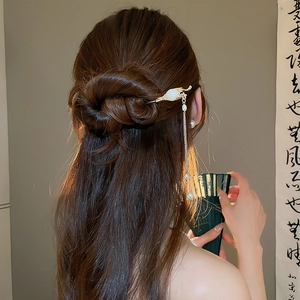 Vue détaillée d'épingle à cheveux chinoise dorée avec glands en perles et jade synthétique