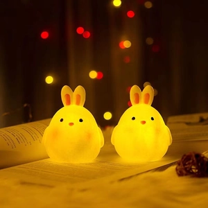 Close-up of cute rabbit night lights with warm yellow glow on an open book