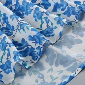 Detailed close-up of blue floral chiffon fabric with elegant pleated layers and texture