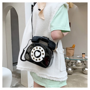Detail of creative black patent leather crossbody bag in a retro telephone design