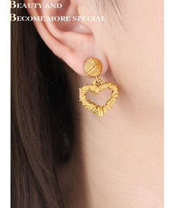 Detail of model wearing gold heart pendant earrings with woven texture and round stud base