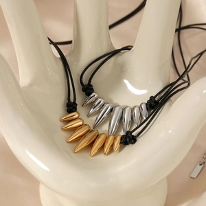Edgy gold and silver spike pendant necklaces on wax cords displayed on a hand model