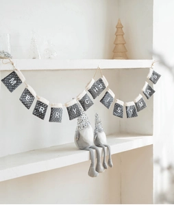Detail of grey felt Merry Christmas letter banner with two Nordic gnome plush figurines