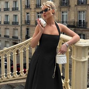 Elegante abito nero a lupetto con mini borsa trapuntata bianca su un balcone classico