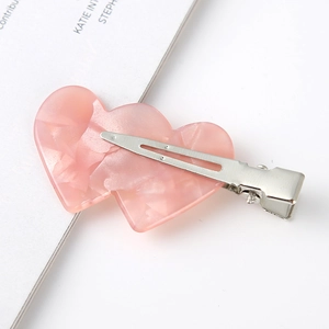 Detail of pink double heart-shaped acetate hair clip with silver metal alligator grip