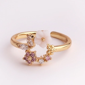 Detail of adjustable gold ring with white flower and pink zircon heart accents