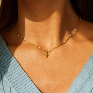 Detail of s925 silver cross necklace with colorful enamel beads on a gold chain
