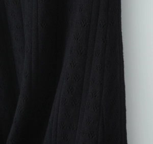Détail de maille côtelée noire avec texture pointelle délicate et ajourée sur la robe