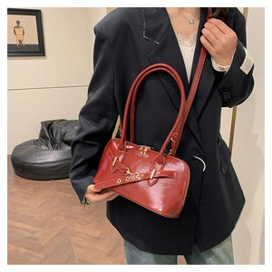 Close-up of red patent leather shoulder bag with sleek gold hardware and top handle