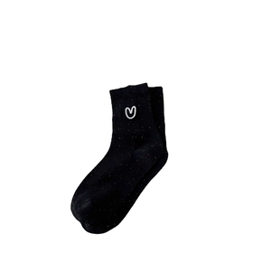 Black cotton crew socks with colorful speckles and white heart embroidery on a white background