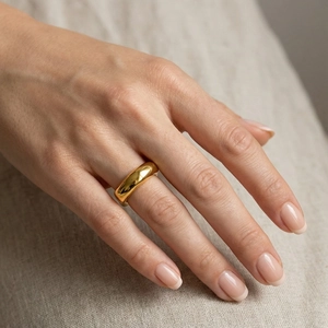 Close-up of minimalist 18k gold plated stainless steel ring on finger with mirror finish