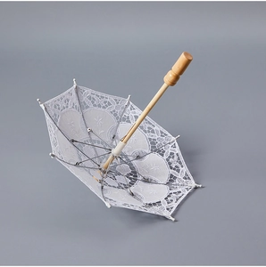 Detailed interior view of white lace bridal umbrella with wooden handle and floral embroidery