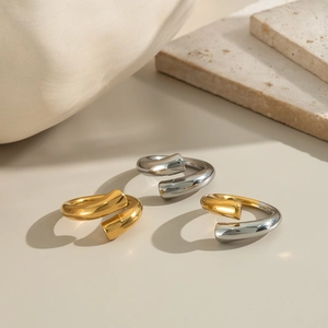 Minimalist adjustable bicolor gold and silver twist rings on a neutral stone display