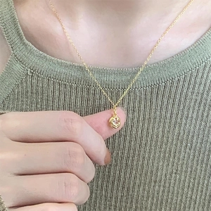 Detailed close-up of a minimalist gold pendant necklace held to show its actual small size