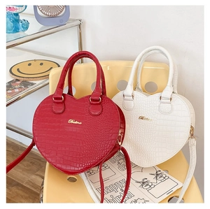Détail d'un sac à main en forme de cœur avec motif crocodile en rouge et blanc