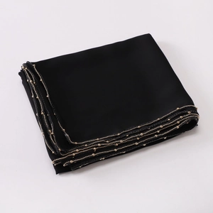 Close-up of black silk-like scarf featuring elegant gold bead chain trim and fine texture
