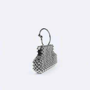 Close-up of silver beaded handbag with metallic beads and a sleek circular handle