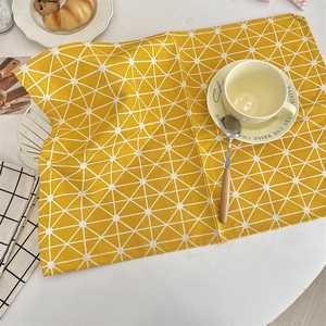 Detail of yellow linen placemat with white geometric triangle patterns for dining table
