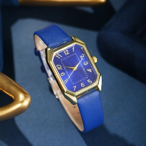 Detail view of blue leather strap and gold rectangular watch case on textured background