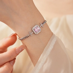 Close-up of elegant silver chain bracelet with square pink stone and zircon on wrist