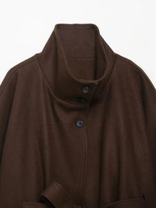 Close-up of the dark brown wool coat collar with refined round buttons and thick texture