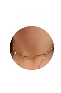Collier à maillons trombone dorés et chaîne délicate portés par un mannequin