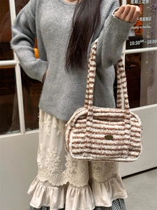 Détail du sac bandoulière rayé en fausse fourrure marron et beige avec plaque logo métal