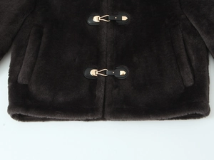 Detailed view of dark brown faux fur jacket featuring elegant gold metal toggle fasteners