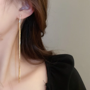 Close-up of golden tassel earrings with rhinestones on model for a luxury look