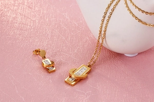 Detailed view of gold jewelry set with geometric Roman numerals and white crystals