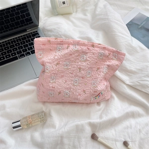 Detailed top view of pink cartoon bunny makeup bag with flowers on white fabric