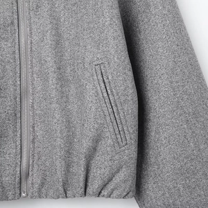 Detail of grey wool bomber jacket with silver metal zipper and heathered fabric texture
