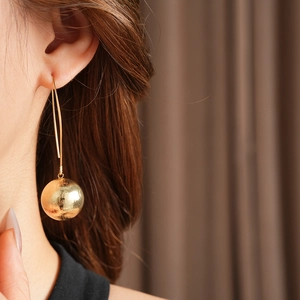 Gros plan d'une boucle d'oreille dorée sphérique à texture martelée sur un mannequin
