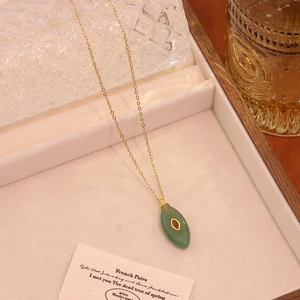 Détail d'un collier vintage doré avec pendentif vert et pierre rouge de style français