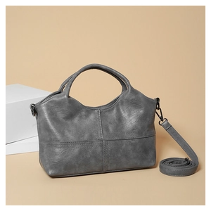 Detail of grey soft leather handbag showing crossbody strap and fine cross stitching